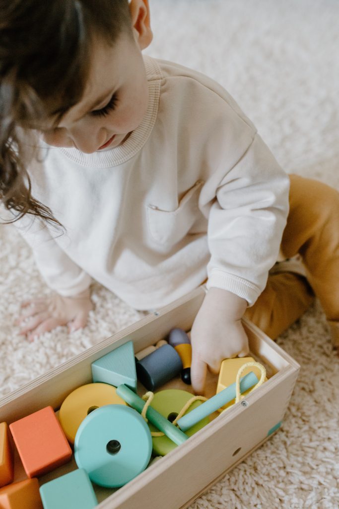 Niño jugando con una cesta de juguetes de madera lista para usar